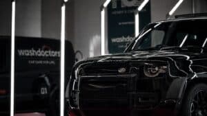 Black luxury SUV inside Washdoctors car detailing centre with bright lighting.