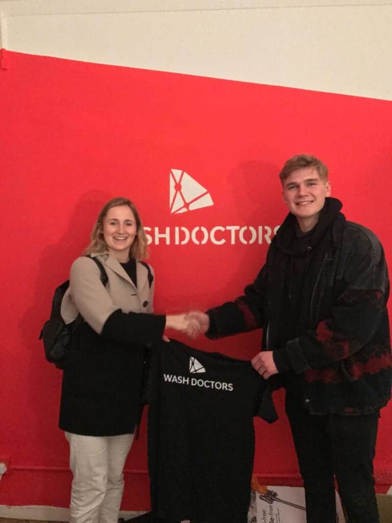 Two young people shaking hands in front of Washdoctors logo.