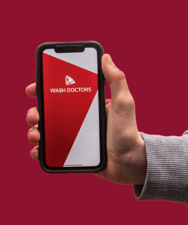 Wash Doctors logo displayed on a smartphone held in hand against a red background.