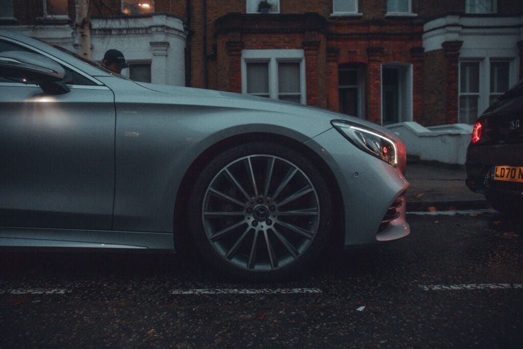 Mercedes alloy wheel and front wing on a wet London terrace street at dusk in winter